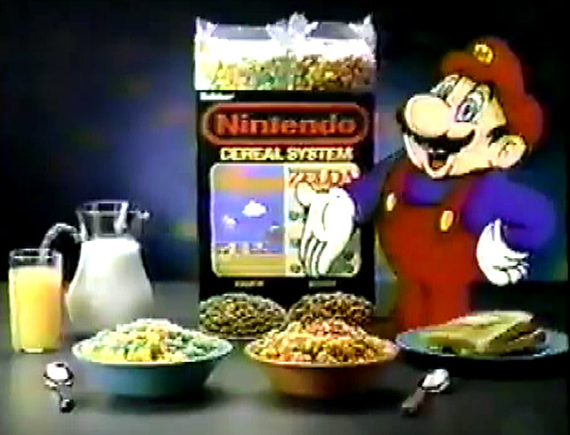 nintendo system cereal tv ad showing 2 bowls of cereal of different colors and Super Mario standing next to box of cereal with milk and orange juice with toast