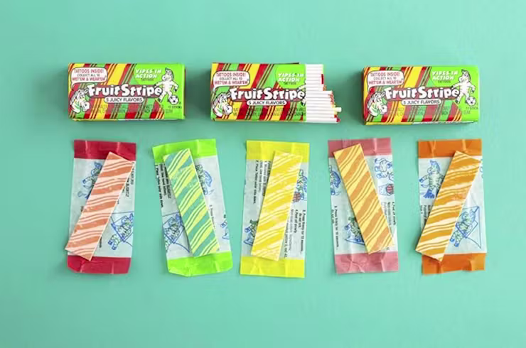 packages of fruit stripe gum in different flavors on a blue green background