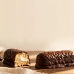 A chocolate-covered snack cake beside a cut piece showing vanilla filling.