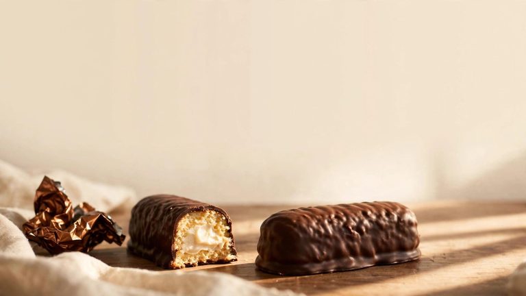 A chocolate-covered snack cake beside a cut piece showing vanilla filling.